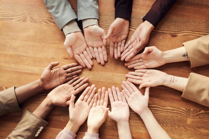 pexels photo 3184397 3184397 1 Top view of diverse hands forming a circle on a wooden table, symbolizing unity and diversity.